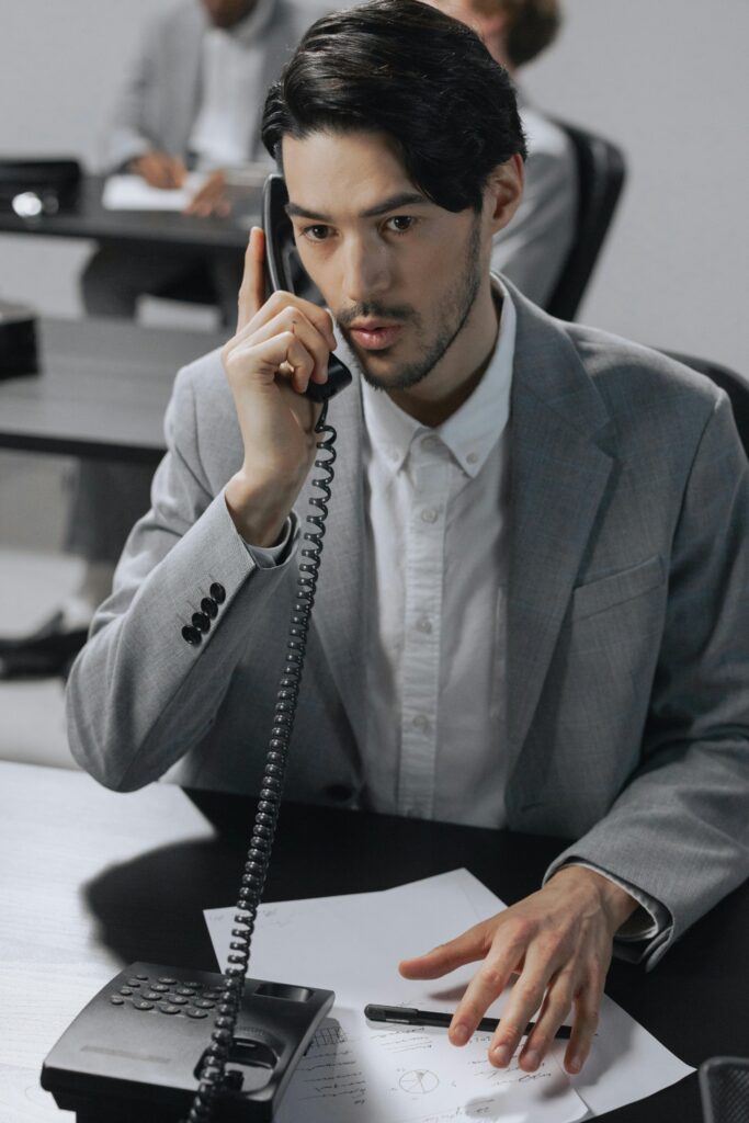 Young man in a suite answering a phone call on a business phone at a burn injury law firm